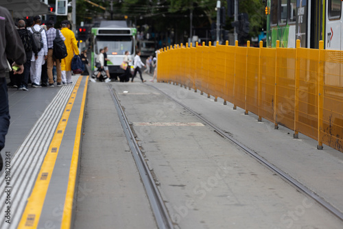 A city tram on a Melbourne street with pedestrians and tracks photo