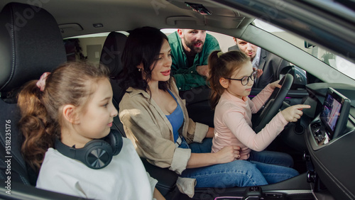 In a modern car dealership, a manager shows and advises a young family with children about buying or test driving a modern car. The concept of buying or leasing a new car.