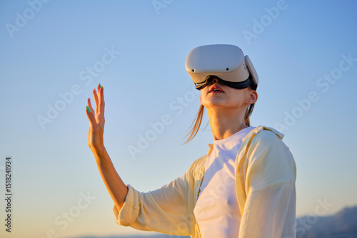 Young woman exploring virtual reality outdoors at sunset