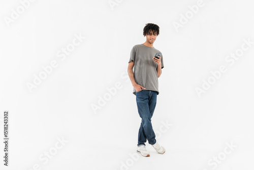 Full body of young smiling male student black man guy boy in casual clothes standing holding using mobile cell phone isolated on plain white background studio portrait copy space
