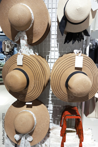 Summer straw hats and a beach bag on display in a shop window.
