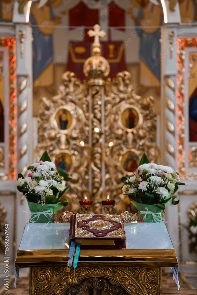 Fototapeta premium Orthodox Church Altar: Golden Iconostasis, White Flowers, Candles, Books Religious Ceremony Setting Inside a Beautiful Eastern Christian Temple