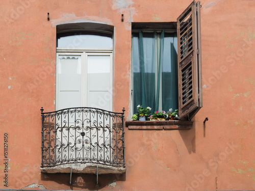 Detail of a building facade. Small balcony with French window and window next to it.