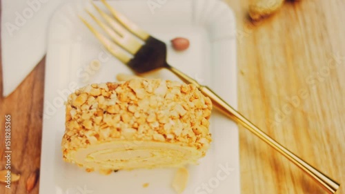 Waviness effect of The woman takes a piece of cake rolled with peanuts with a gold fork. In the background are peeled peanuts on a retro-style cooking tray. Macro and slider shooting