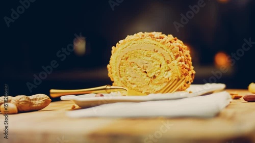 Waviness effect of The woman takes a piece of cake rolled with peanuts with a gold fork. In the background are peeled peanuts on a retro-style cooking tray. Macro and slider shooting