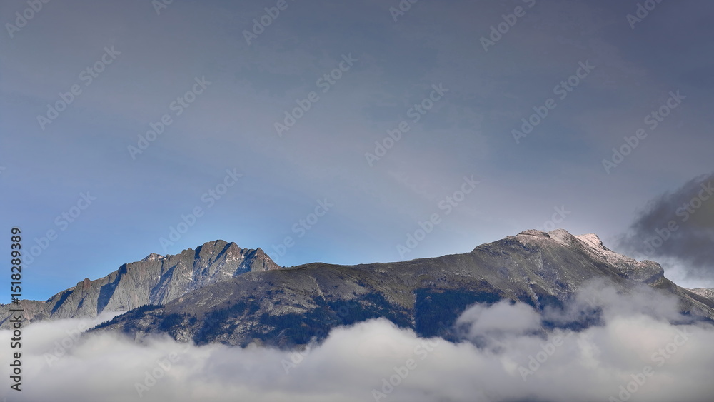Fototapeta premium Mount Colin and Roche Bonhomme, in the Colin Range, rise from the sea of clouds below them to the blue sky with wispy clouds. Jasper NP-AB-Canada-259