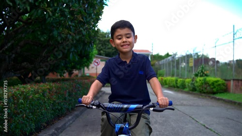 Latino boy learning to ride his bike and starting to go very slowly in his neighborhood