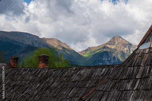 Traditional wooden house in Ždiar, Slovakia, with view of High Tatras peaks — Ždiarska vidla, Hlásna skala and Široké sedlo — symbol of harmony between heritage and mountain nature. photo