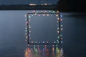 Square frame of colorful lights hanging above water at night