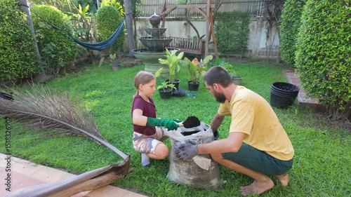 Father and daughter planting in backyard garden on sunny day
