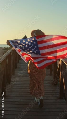 Female jogging on wooden jetty, gripping american flag, celebrating national pride during golden hour sunset, radiating freedom and enthusiasm. Usa celebrate 4th of july. Independence day concept