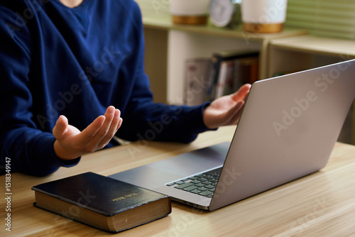 Christian online technology concept. Hands praying of christian with digital computer laptop, Online live church for sunday service. Asian catholic man are reading Holy bible book and online study.