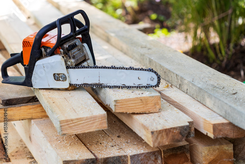 An old chainsaw that sawed through a lot of boards is located on freshly sawn wood