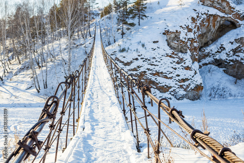 a suspension bridge in winter across an ice-covered river