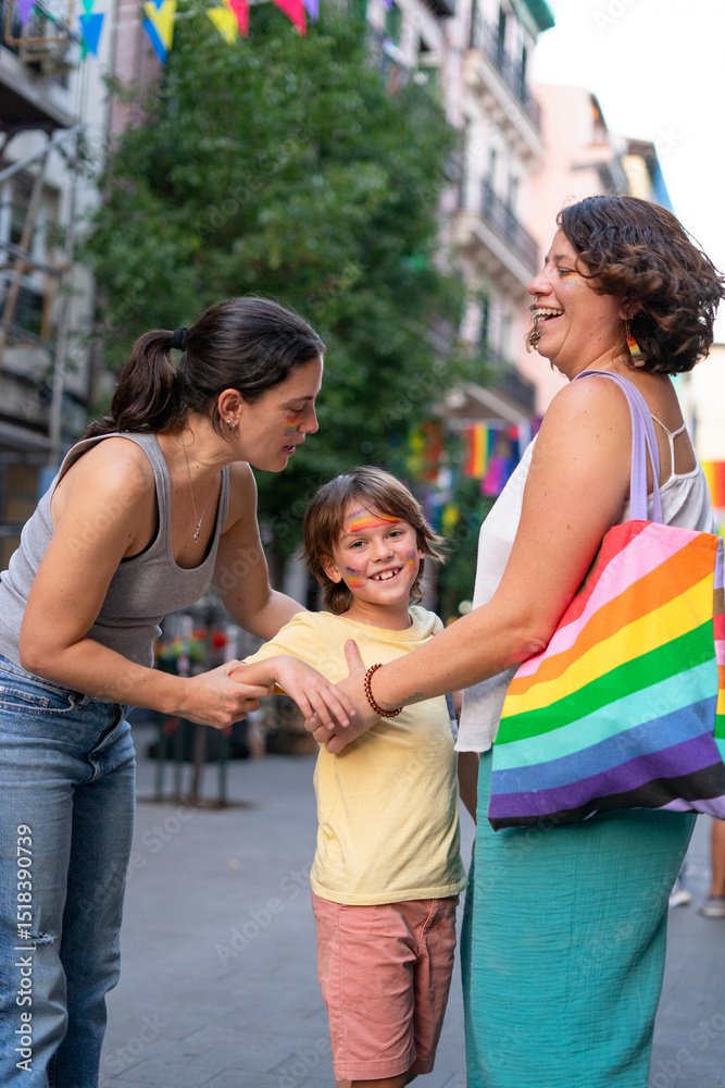 Fototapeta premium Mothers holding hands with son at pride parade celebrating lgbtq+ rights