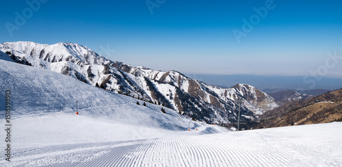 Famous Shymbulak mountain ski resort view with beautiful white and snowy ski lines, cable-way, blue sky, fresh air. Wonderful picturesque resort for holidays and travelling near Almaty