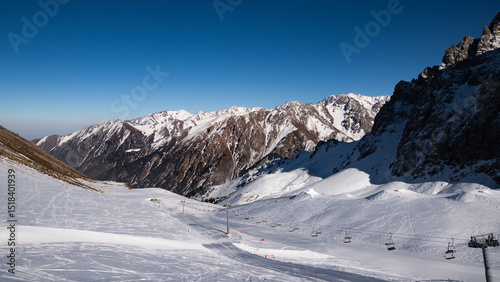 Famous Shymbulak mountain ski resort view with beautiful white and snowy ski lines, cable-way, blue sky, fresh air. Wonderful picturesque resort for holidays and travelling near Almaty