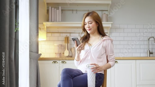 A casual Asian woman in sporty attire takes a break after home workout, sitting on the floor and using her smartphone to interact with an AI assistant, checking health data, fitness stats, and body me