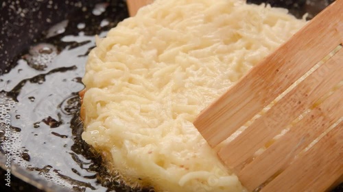 Wooden spatula flips hash brown potatoes in a frying pan. Close-up. High quality 4k footage