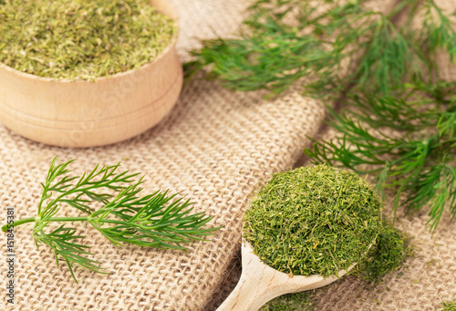 Dried chopped dill in a wooden bowl and sprigs of fresh dill