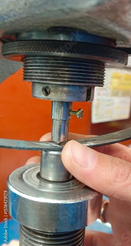 The worker's hand measures the hardness of a spring on a hardness tester using the Rockwell method