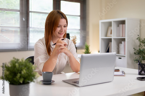 Young woman working on a white desk with a laptop.