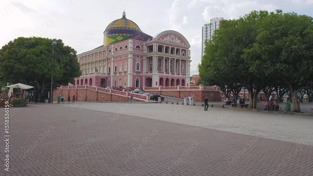 Vista aérea do majestoso Teatro Amazonas, joia arquitetônica em Manaus, cercado pela floresta urbana e céu azul, símbolo da cultura e história amazônica.