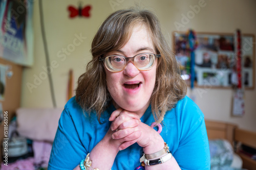 Portrait of a 42 yo happy woman with Down Syndrome in her sleeping room in Tienen, Flemish Brabant Region, Belgium