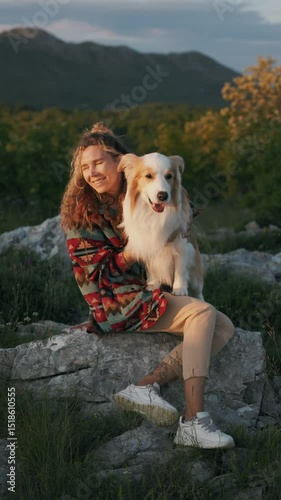 Beautiful mountain view with a girl and a border collie dog. A girl strokes and laughs with her pet