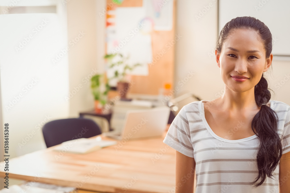 Asian woman standing at wooden desk in bright workspace using open laptop and notebooks, copy space Asian woman standing at wooden desk in bright workspace using open laptop and notebooks, copy space