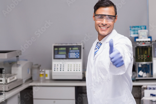 Male lab tech wearing lab coat operating analyzers in clinical lab with reagent bottles, copy space