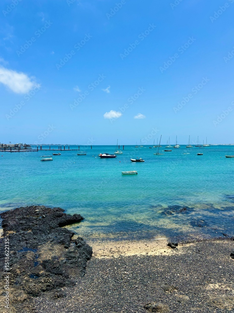 Fototapeta premium Turquoise ocean water of Corralejo harbor in Fuerteventura, Canary Islands, Spain, summer time, vertical photo