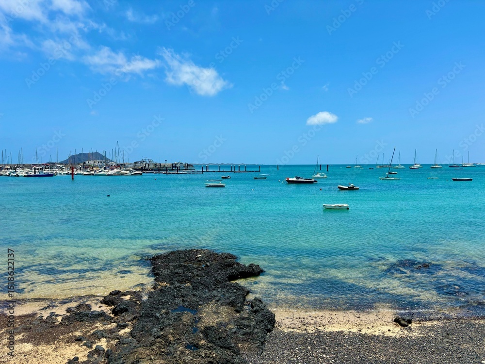 Fototapeta premium Turquoise ocean water of Corralejo harbor in Fuerteventura, Canary Islands, Spain, summer time, exotic vacations