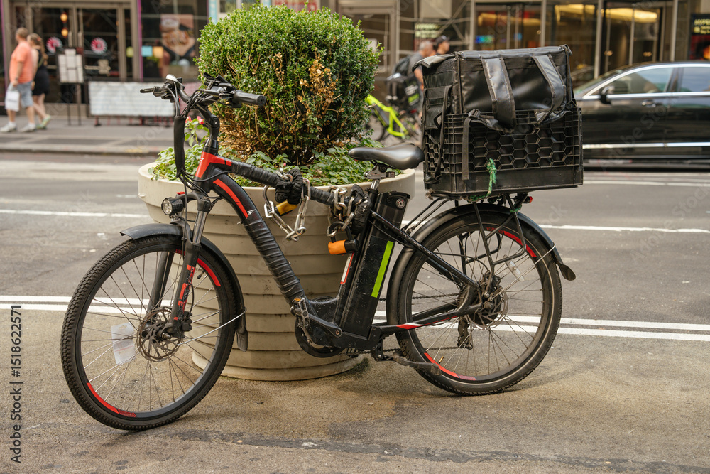 custom made wallpaper toronto digitalAn electric delivery bicycle with a large rear cargo box is parked near a planter on a busy New York street. The scene reflects urban life, gig economy work, and eco-friendly transportation.