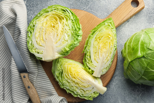 Foto Fresh cabbages and knife on grey table, flat lay