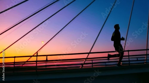 Silhouette of runner on a bridge at sunset