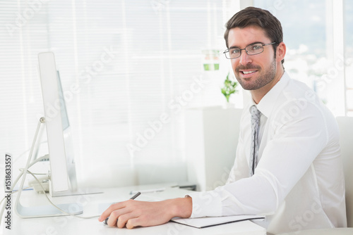 Man wearing business attire working at office desk with monitor, notebook, copy space