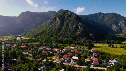 Drone video capturing the serene landscape of Ortaca, with houses nestled amidst greenery and a majestic mountain backdrop