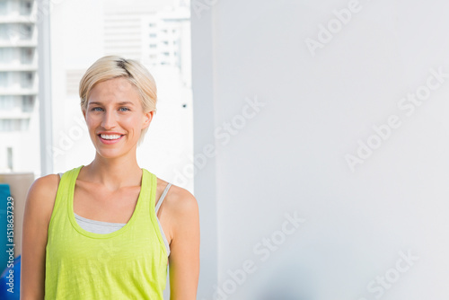 Free Download Woman wearing lime top standing in fitness studio by windows showing city buildings, copy space - GFXLoad