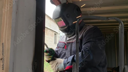 The welder works with a welding machine. A builder uses a welding machine to make a window frame.