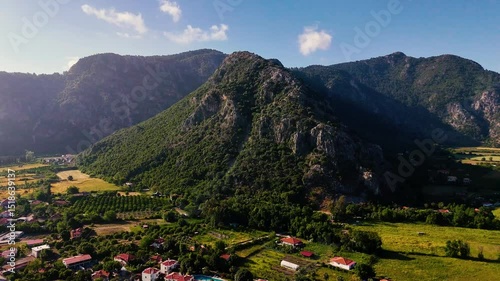 Drone video capturing the serene landscape of Ortaca, with houses nestled amidst greenery and a majestic mountain backdrop