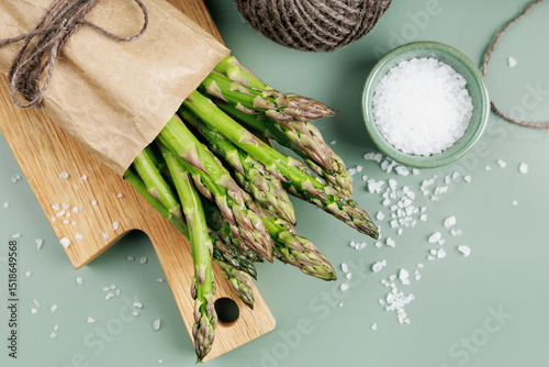 Flat lay of asparagus with sea salt and twine on green background