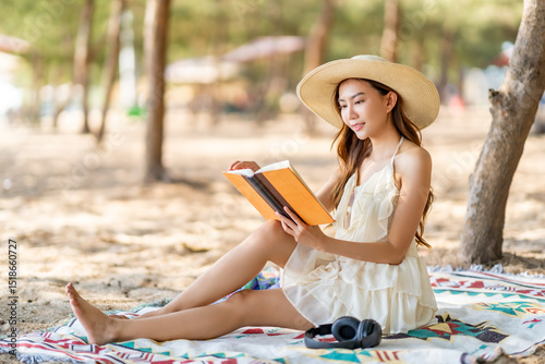 Happy Asian woman travel the sea on summer beach holiday vacation. Attractive girl enjoy outdoor lifestyle travel nature, social media detox relaxing and reading a book on tropical beach in sunny day.
