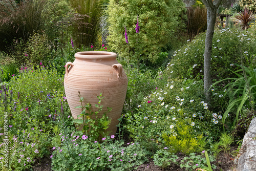 terracotta clay pot with flowers in a garden