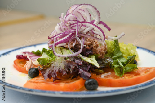 Salad with tuna, tomato, onion and herbs on a plate