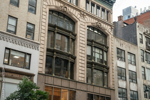 Wallpaper Mural Close-up view of a historic building in New York City with decorative arched windows and intricate stone detailing. The dark-framed bay windows contrast elegantly with the beige facade. Torontodigital.ca