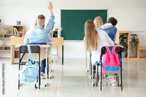Classmates raising hands to...