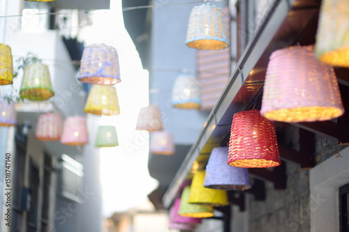 Fototapeta Naklejka Na Ścianę i Meble -  Decorative multicolor wicker lamps are hanging under the street in a small European town