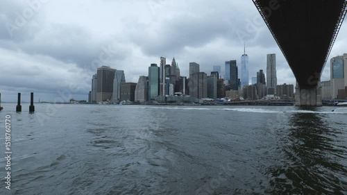 New York City, USA - May 21, 2025: A view of the downtown Manhattan from under the bridge across East River.