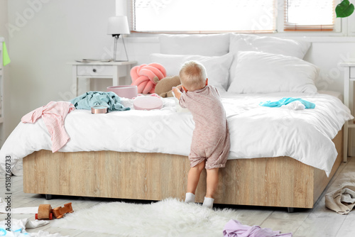 Naughty baby boy in messy bedroom, back view